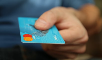 Gros plan d'une main tenant une carte bancaire bleue