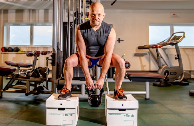 Un athlète se tient debout sur deux boîtes d'archives Merak pour montrer sa force