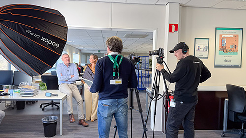 Cameracrew filmt Sven en Mireille in een kantooromgeving voor een interview over archiveren en scannen bij Merak.
