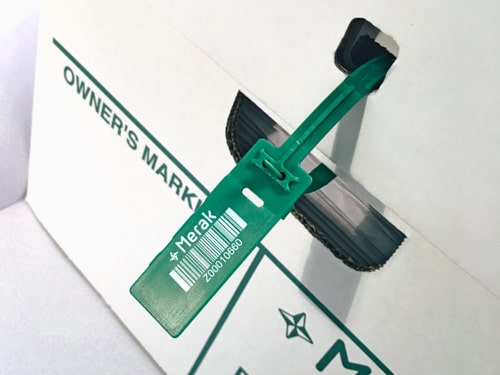 Sceau en plastique vert avec code-barres blanc attaché au couvercle d'une boîte